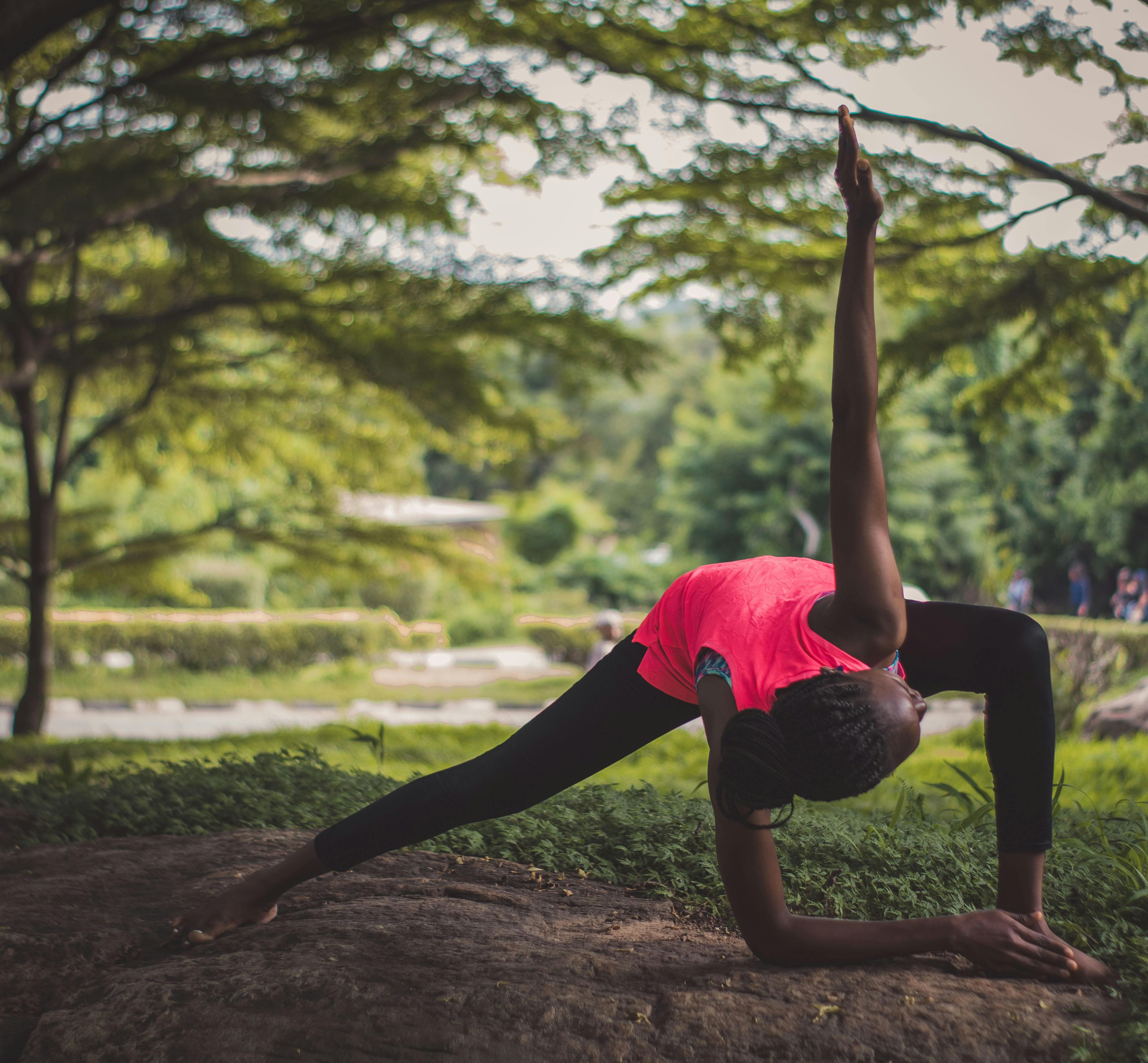 oudoor woman doing yoga in a park with a vibrant city skyline in the background